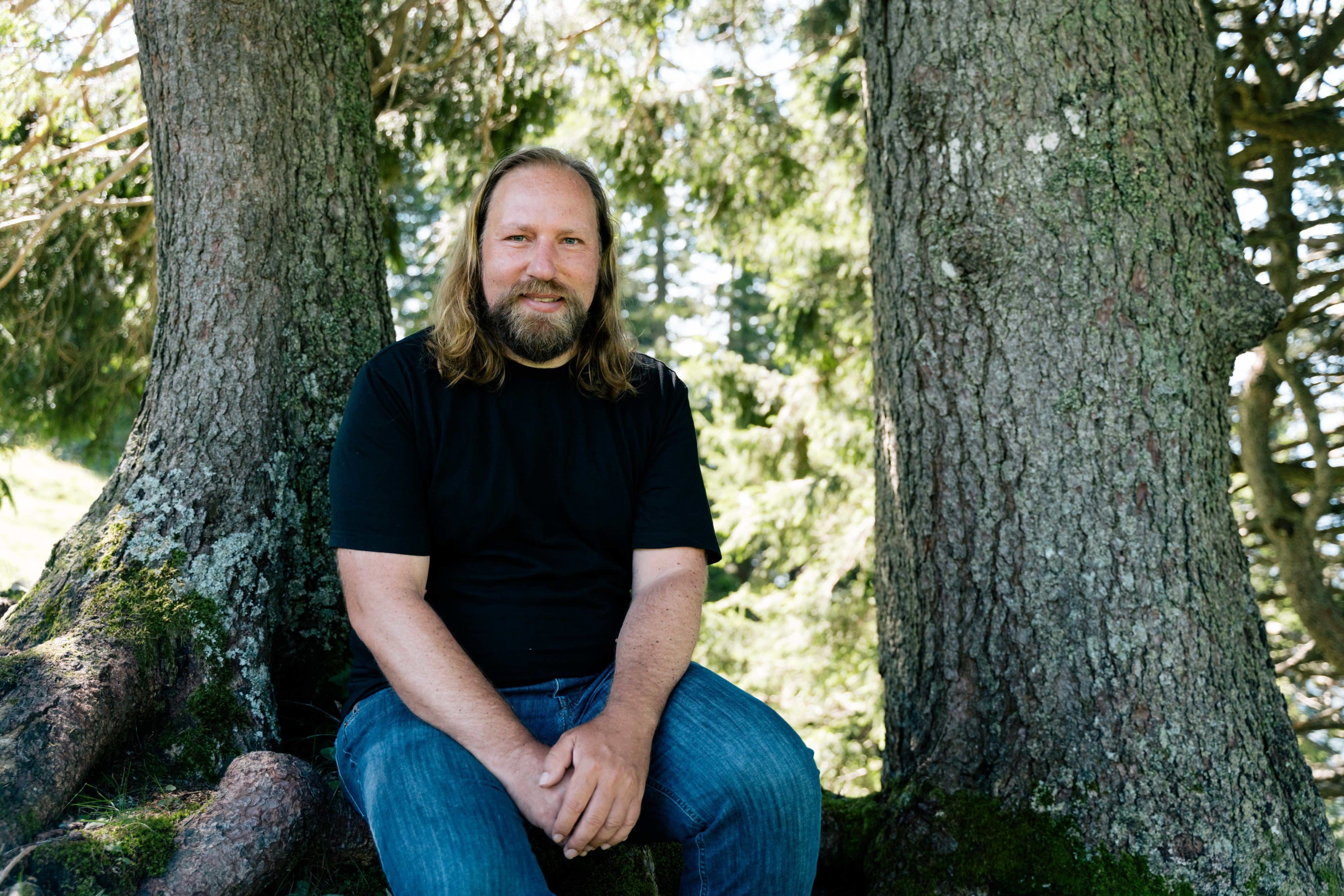 Anton Hofreiter sitzend vor zwei Bäumen in der Natur