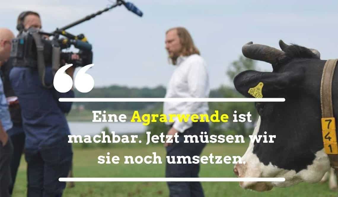 Toni steht im Hintergrund. Es ist eine Kuh zu sehen. Auf dem Bild steht der Text: "Eine Agrarwende ist machbar. Jetzt müssen wir sie noch umsetzen."