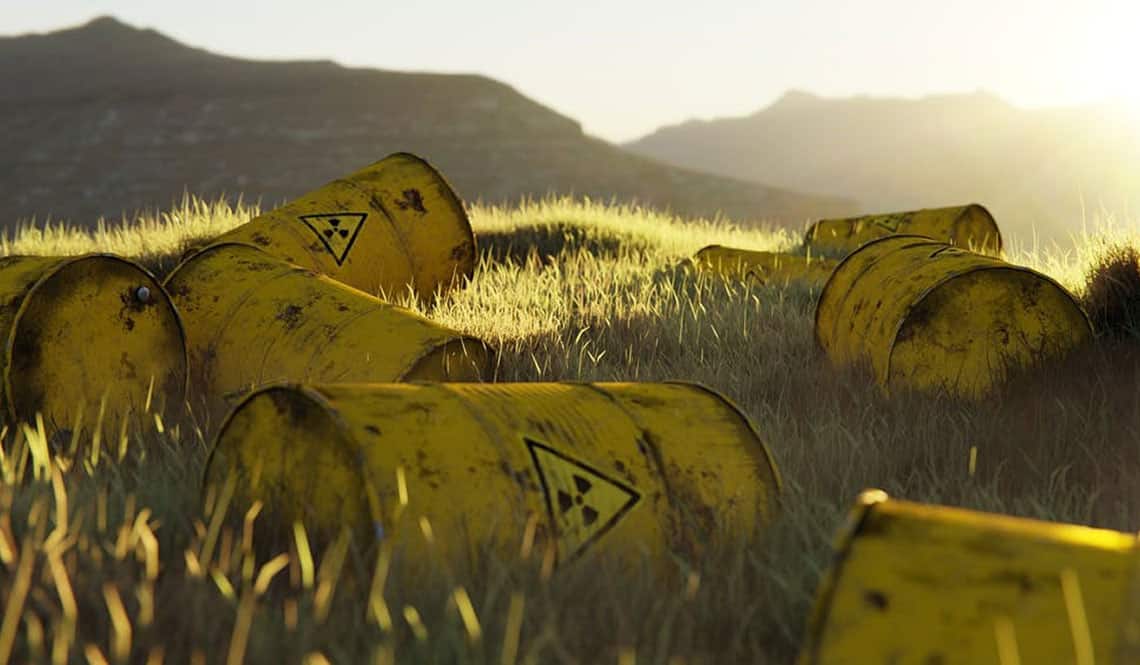 Gelbe Tonnen, auf denen der Warnhinweis vor Atommüll angebracht ist. Sie liegen in der freien Natur auf Gras.